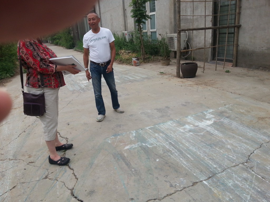 Artist Zhang Wei and Debbie inspecting how he paints using his motorcycle in his driveway.