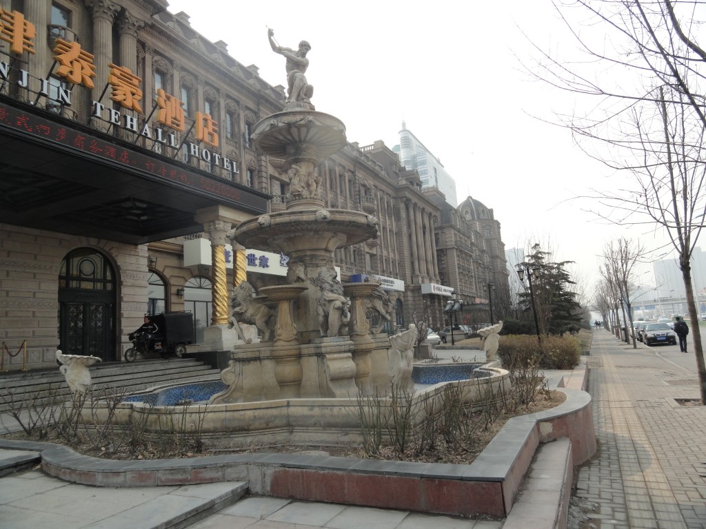 shot of fountain and front of Tehall Hotel showing neon Chinese character signs
